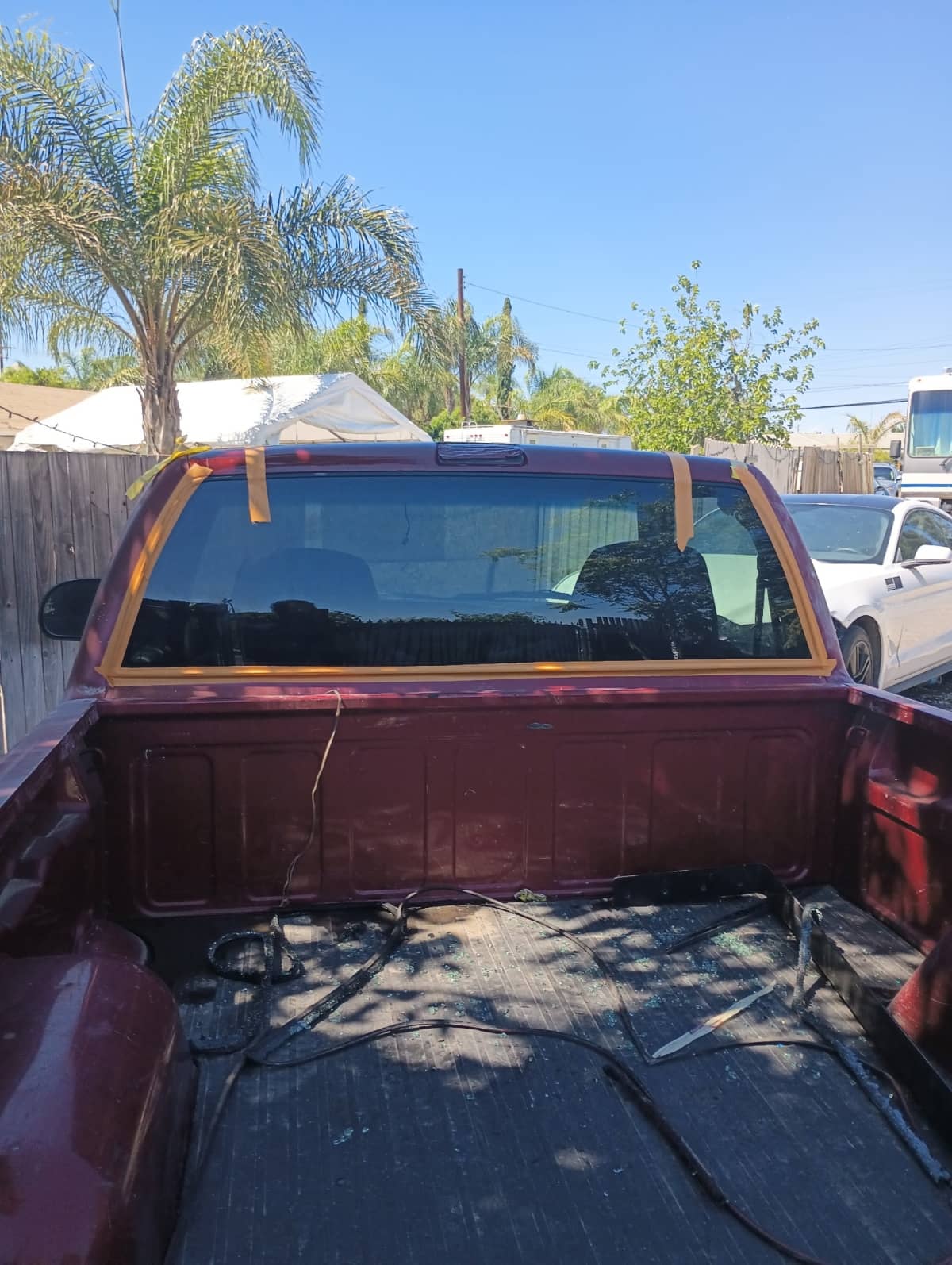 Newly installed back glass taped in place on a maroon pickup truck